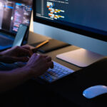 Developer performing software maintenance on a desktop computer, representing continuous system updates and managed IT support services
