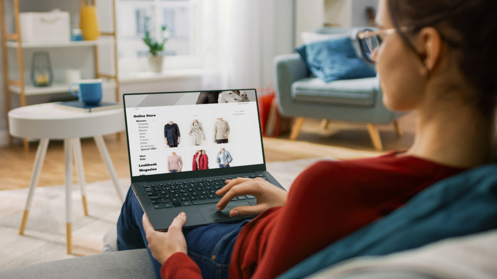 Kobieta przeglądająca na laptopie ubrania w sklepie intenetowym