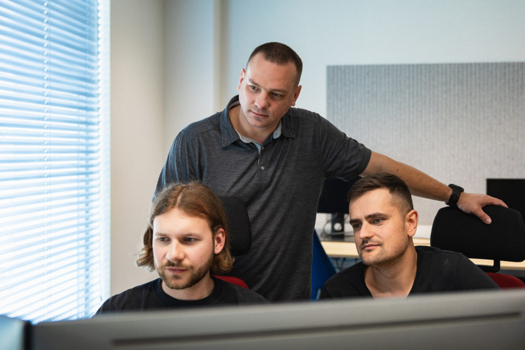 Team members of Spyrosoft looking at a computer