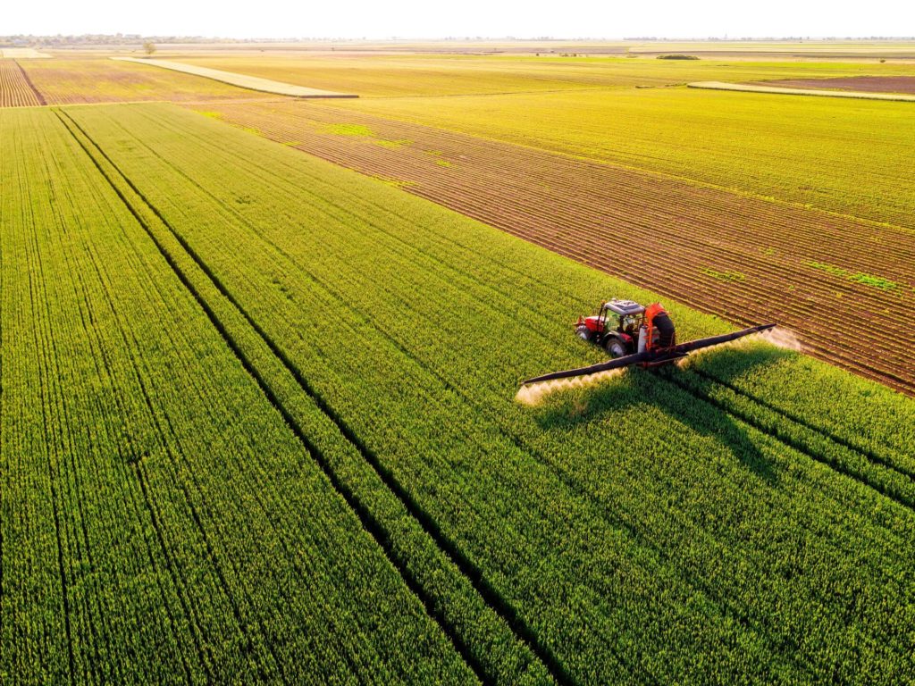 Aerial view of a farmer driving a tractor on a green field of a innovative agricultural business