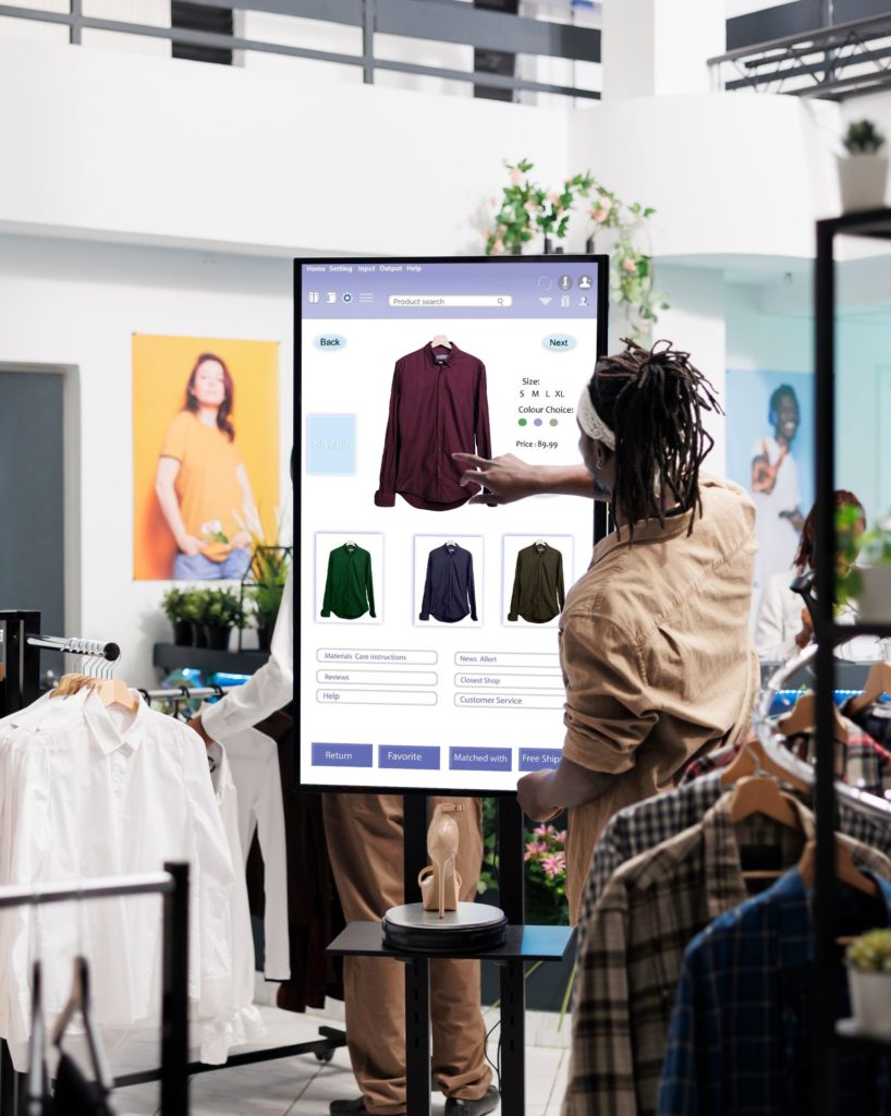 A customer in front of a touchscreen in a clothing shop, using modern retail and digital solutions.