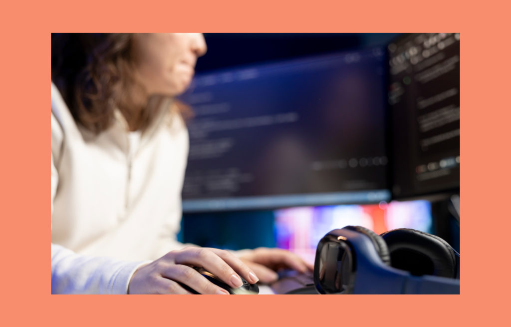 Software developer working on a computer with code on screen, illustrating cybersecurity risks in media and entertainment