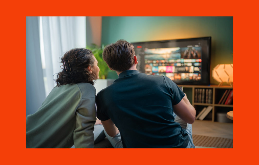Couple sitting on a couch browsing a streaming platform on a smart TV, representing Apple TV app development and user experience design