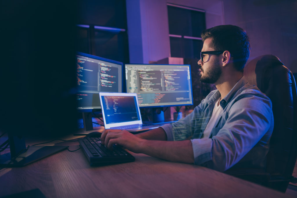 Profile side view portrait of a skilled smart focused, concentrated guy consultant writing script creating new digital desktop app in dark room workplace station indoors