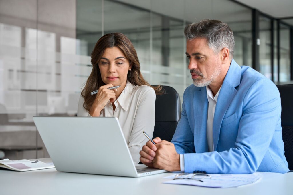 Insurance consulting and technology services. Team of two busy insurance agents using laptop in discussion about insurance options